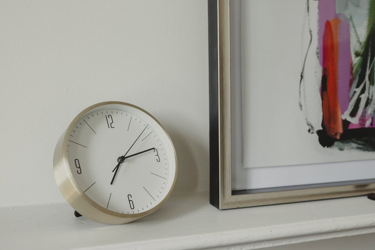 Brass clock and a framed abstract painting on a white mantel