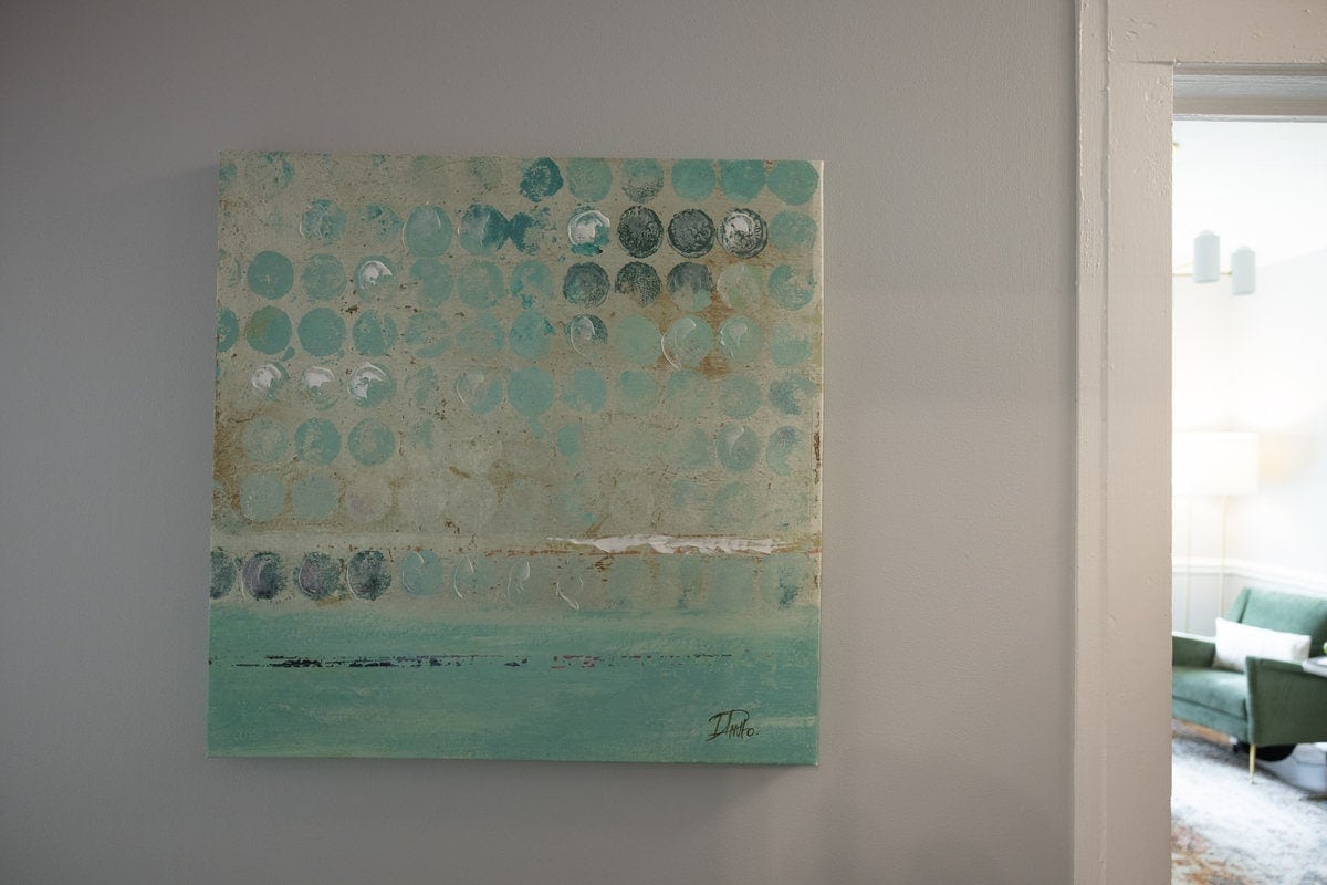 Teal circle painting in a Lexington hallway, with a green chair in the next room