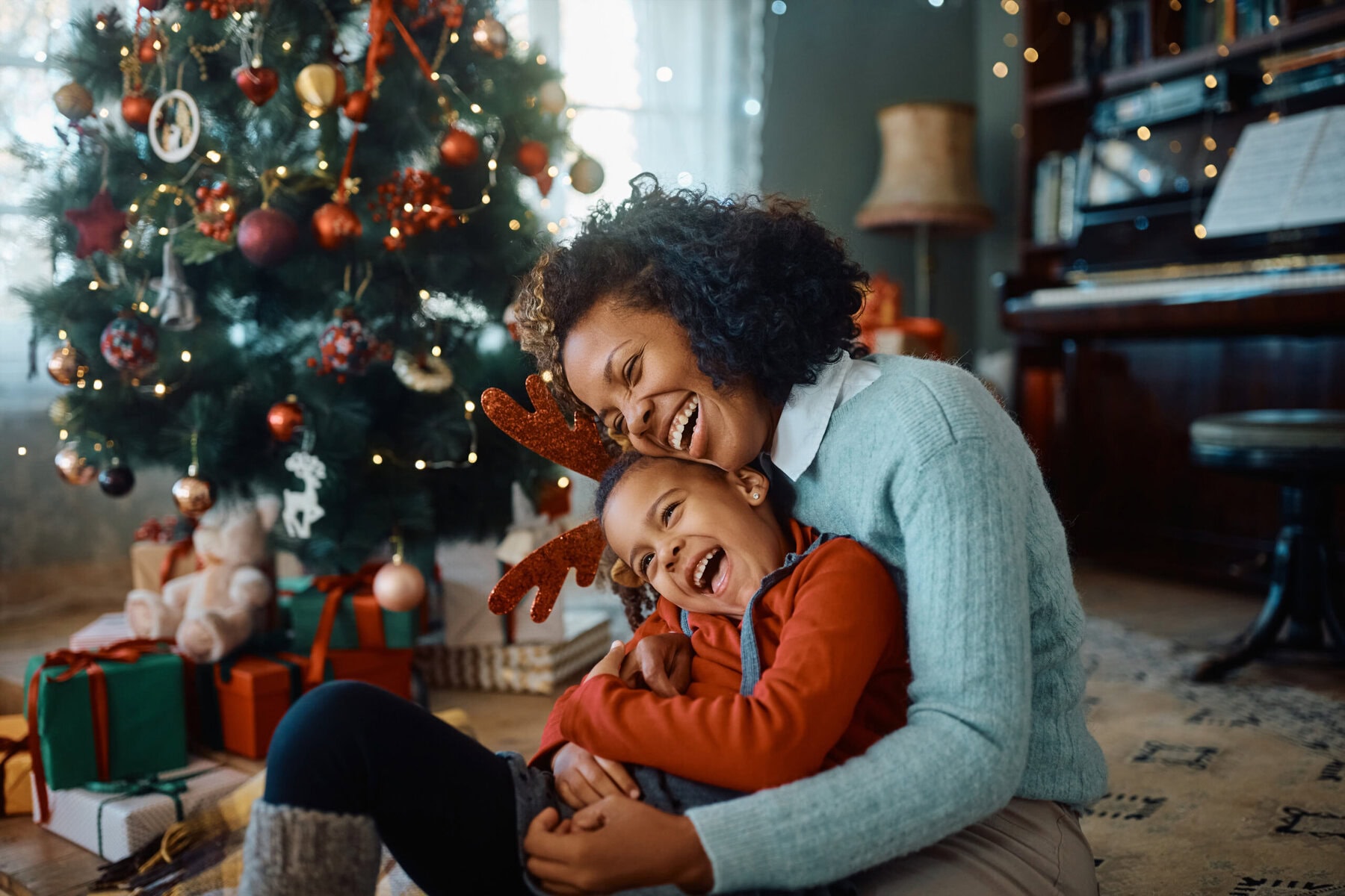 Parent and child laughing together beside a Christmas tree
