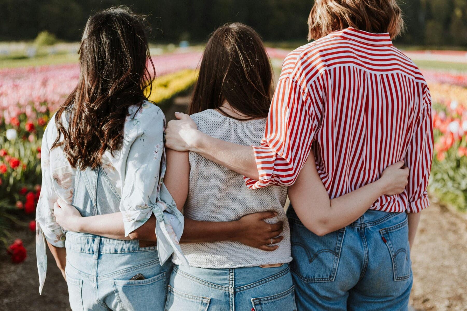 Three people standing together with their arms around each other