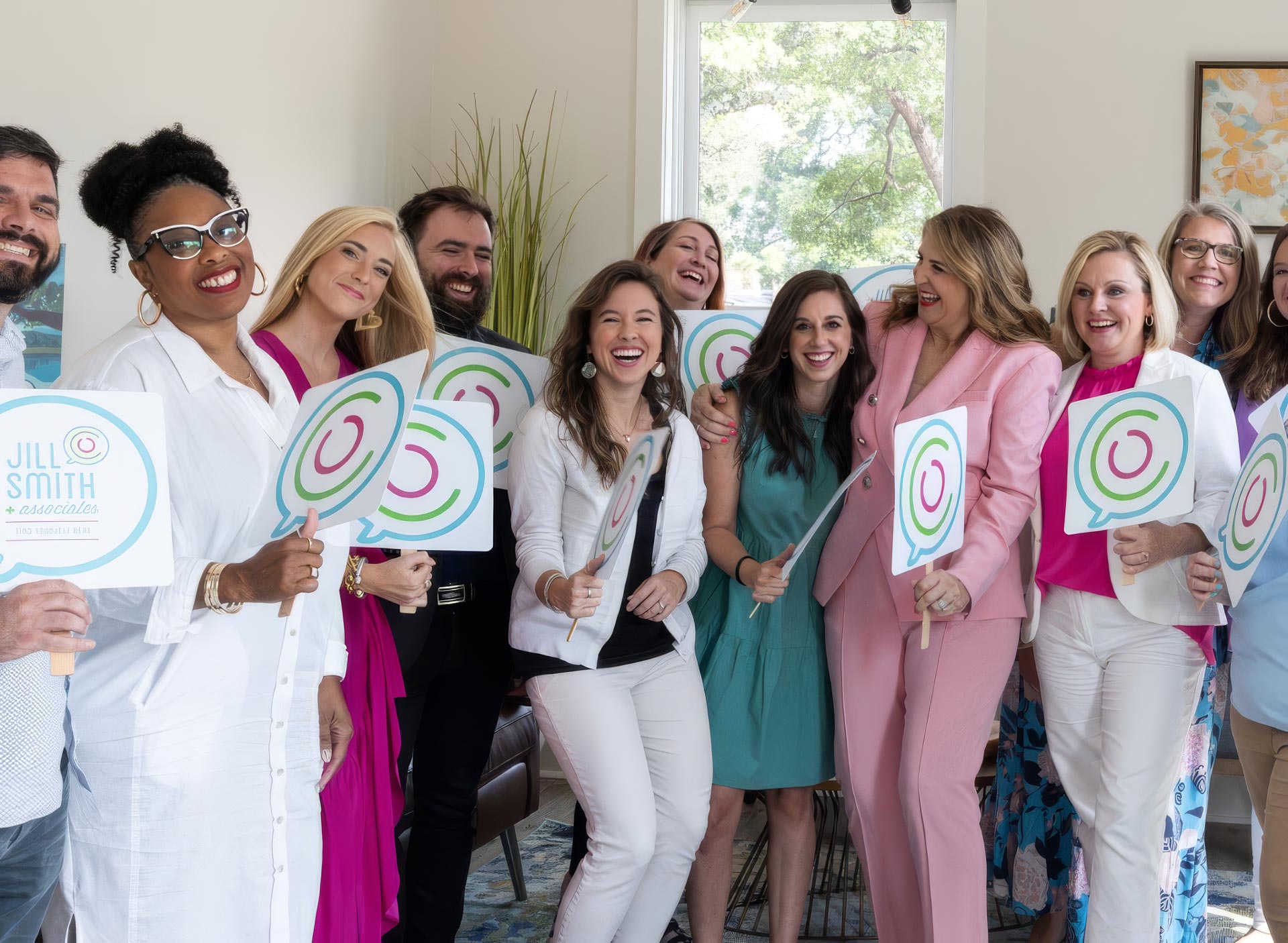 The Jill Smith & Associates counseling team smiling together in the office, holding Find Yourself Here signs