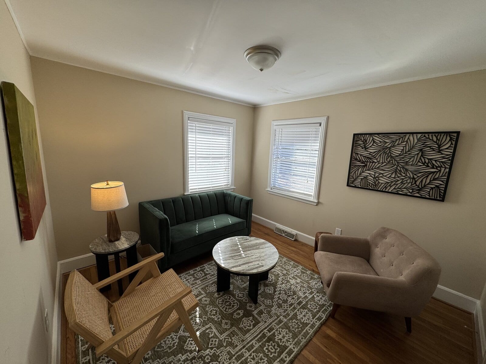 Blythewood session room with a green sofa, cane chair, and marble coffee table