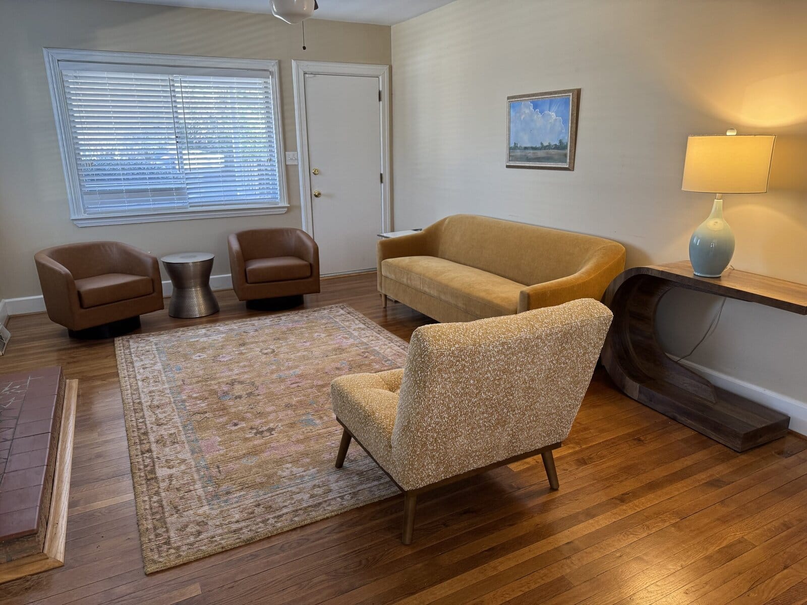 Blythewood seating area with leather chairs, a mustard sofa, and a window with blinds