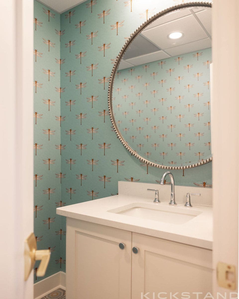 Columbia powder room with dragonfly wallpaper, a round mirror, and a white sink