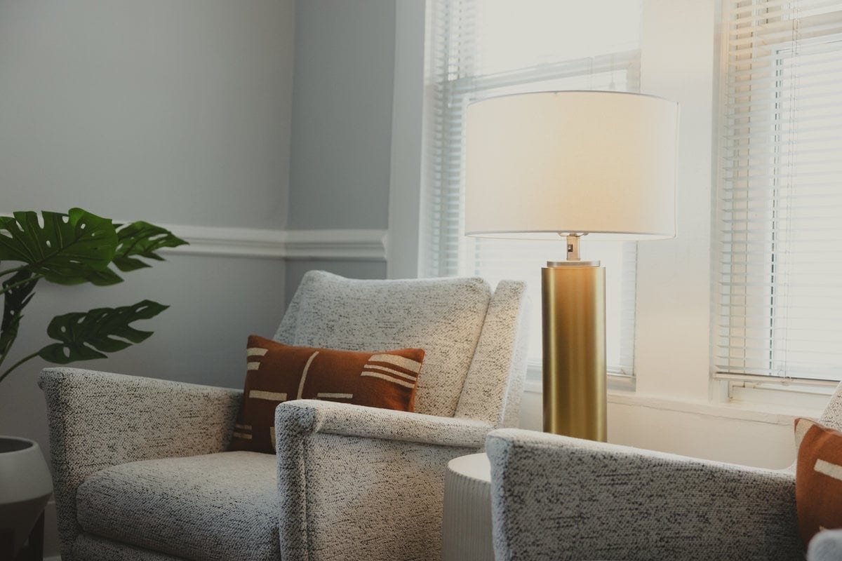 Textured armchairs and a brass lamp by a window in the Lexington office