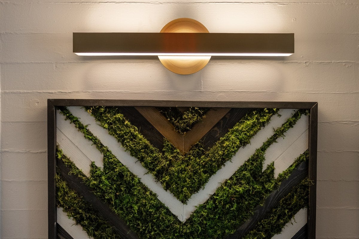 Moss and wood chevron artwork with a brass light in the Lexington office