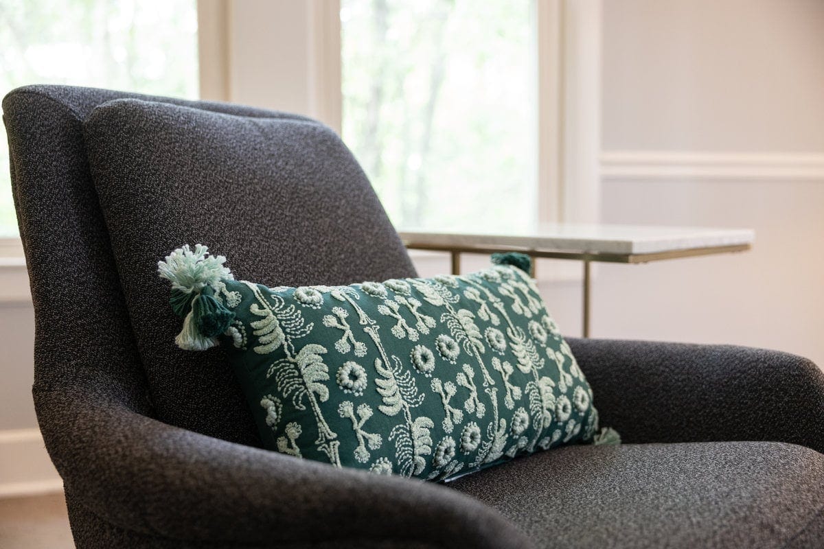 Gray armchair with an embroidered green pillow in a Lexington counseling room
