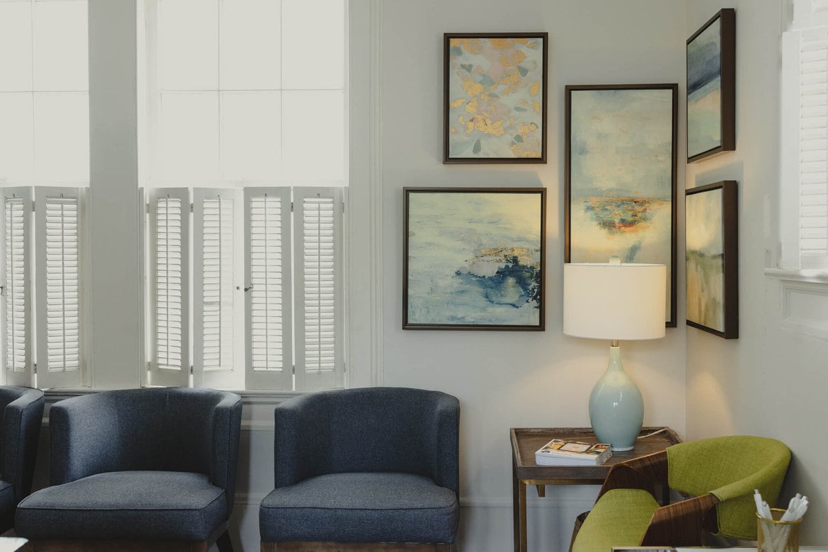 Lexington waiting area with blue chairs, a green chair, and a gallery wall